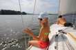 © Pavel Losevsky - Girl in white cap sits and man lies on yacht during sailing on river at sunny summer day