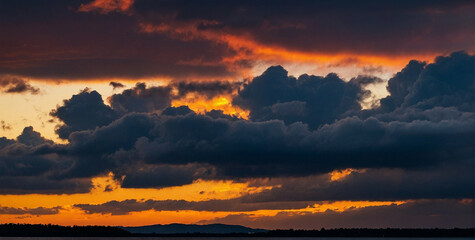 Wall Mural - Vivid Sunset Over a Serene Landscape With Dramatic Clouds