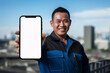 © vectornation - Asian mechanic man showing blank screen smartphone on blurred city background