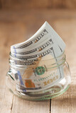 Fototapeta Koty - Dollar bills in glass jar on wooden background. Saving money concept.