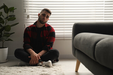 Wall Mural - Sad man sitting near closed blinds indoors