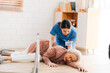 senior patient falling on the ground floor at home, Asian caregiver helping elderly older female from accident after doing physical therapy then rescued by attractive therapist nurse, health insurance