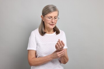 Wall Mural - Arthritis symptoms. Woman suffering from pain in wrist on gray background