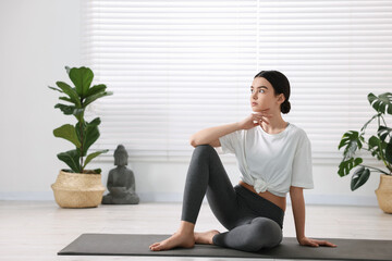 Wall Mural - Beautiful girl sitting on yoga mat in studio