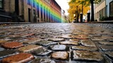 Fototapeta Uliczki - A closeup of rain soaked cobblestone streets with a rainbow