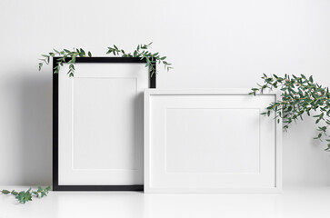 Two picture frames mockup in white room with fresh eucalyptus twigs decoration