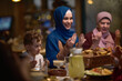 © .shock - In a modern restaurant setting, a European Islamic family comes together for iftar during Ramadan, engaging in prayer before the meal, uniting tradition and contemporary practices in a celebration of