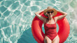 A woman in a red bathing suit is floating in a red inflatable ring in a pool