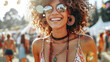 A woman with curly hair and a necklace is smiling at the camera. She is wearing a pair of sunglasses and earrings