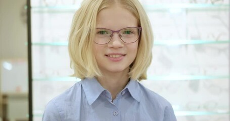 Wall Mural - portrait happy little girl patient ophthalmology clinic, cheerful child putting on eyeglass. good vision.