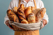 © Tanya - Bakery man in yellow apron holding wicker basket with healthy freshly baked wholegrain breads on a blue background. Healthy eating concept.