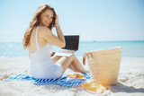 Fototapeta  - smiling stylish female on ocean shore with straw bag