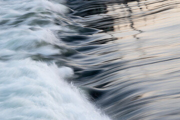 rapid water flow over barrier with silky surface, river overflow over dam close up with splash and f