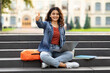 © Prostock-studio - Young eastern woman student using laptop outdoors, showing thumb up