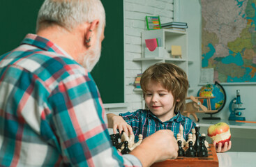 Fototapete - Grandfather and grandson child playing chess. Grandpa teaching grangson at chess school.