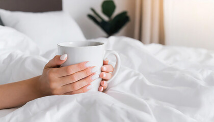 hand s of young woman with coffee mug in bed with white linens minimal happy morning concept