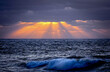 sunset in the ocean. A blue and stormy ocean. Sun rays in the water. Rough ocean. Beautiful sunset in Portugal, golden sun rays