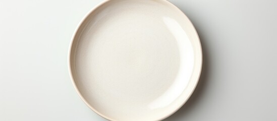 Poster - A porcelain plate from the dishware sits on the tableware, on a white surface. The circleshaped serveware gesture showcases the elegant ceramic design