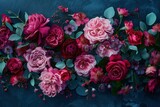 Fototapeta Tulipany - Vibrant red and pink roses on a textured dark blue background.