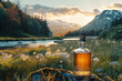 A bottle of whiskey is adjacent to a beautiful mountainous area with a pond