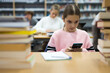 Schoolgirl using mobile phone in the school library
