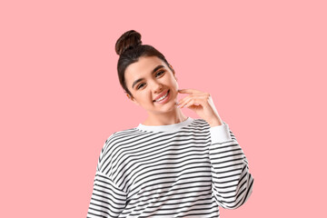 Wall Mural - Pretty smiling young woman on pink background