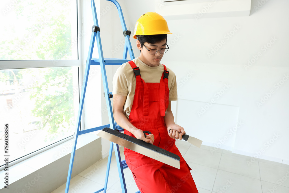 Asian decorator with putty knives in room