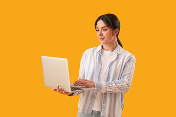 Female programmer working with laptop on yellow background