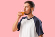 Young man drinking juice on pink background