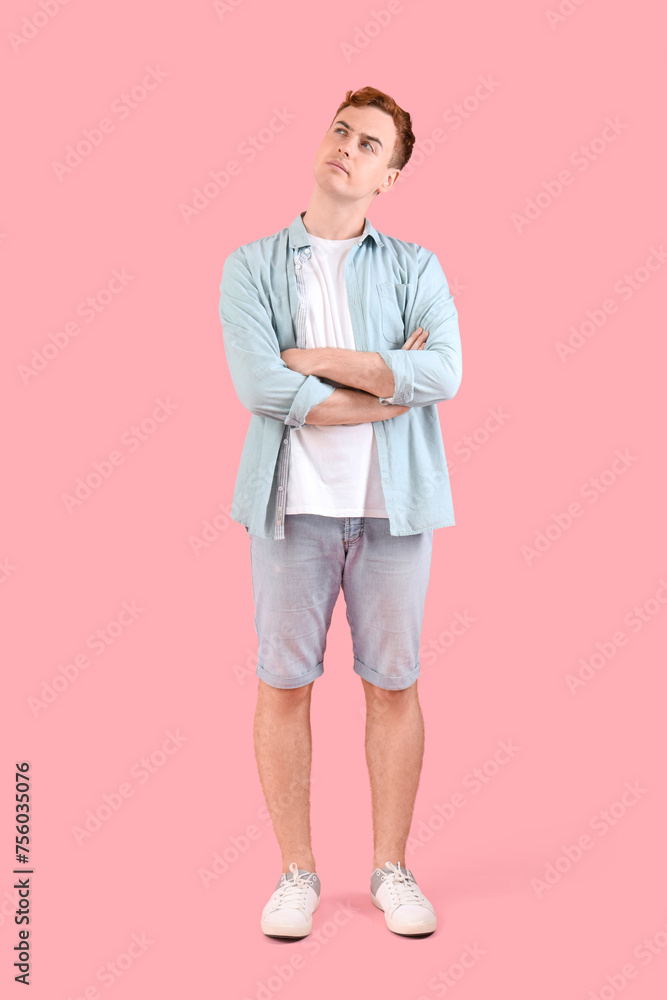 Thoughtful young redhead man on pink background