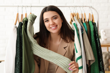 Sticker - Happy female stylist with clothes on rack in studio