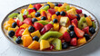 Close up of fruit salad made with mango, kiwis, blueberries, raspberries, strawberries and chia seed on white plate, light background.