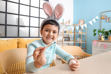 Poster - Cute little boy in bunny ears painting Easter eggs at home