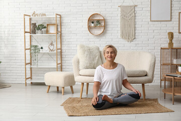 Sticker - Mature woman meditating while sitting on floor at home