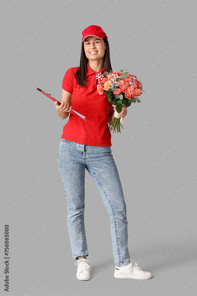 Young delivery woman with bouquet of beautiful flowers and clipboard on grey background