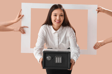 Sticker - Beautiful young happy Asian woman with safe box and hands holding frame on brown background