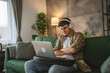 © Miljan Živković - yong man teenager sit at home with headphones watch video on laptop