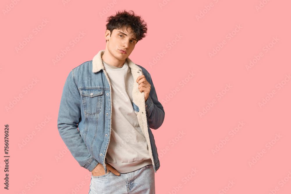 Handsome young man in stylish denim jacket on pink background
