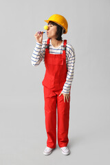 Wall Mural - Funny young female builder with hardhat and party blower on white background. Fool's day