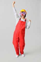 Wall Mural - Young female builder with hardhat and funny glasses on white background. Fool's day