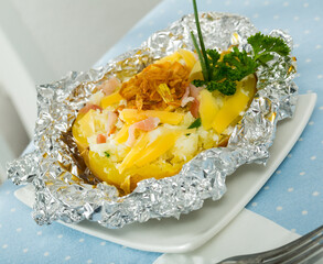 Wall Mural - Tasty cooked in foil baked potato filled of salad with cheese, bacon and fried onion..