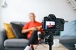 © Gatot - Asian senior influencer man playing guitar during podcast or live video broadcast for the audience from the camera at home