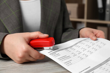 Wall Mural - Woman stapling documents at wooden table indoors, closeup