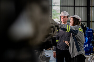 Factory engineer woman inspecting on machine with smart tablet. Worker works at machine robot arm. The welding machine with a remote system in an industrial factory. Artificial intelligence concept.