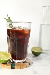 Wall Mural - Refreshing iced coffee with rosemary in glass and fresh lime on white marble table