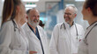 © Kanlayarawit - A group of four senior and young doctors in white coats and stethoscopes are talking and laughing together. White doctors are enjoying themselves with each other on a blurred hospital background.