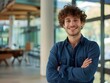 A smiling confident young business man standing with arms crossed in a modern office. a happy handsome curly haired male entrepreneur with his hands folded across his chest. generative AI