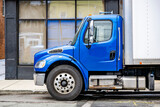 Fototapeta Mapy - Blue middle duty day cab semi truck with box trailer standing on the city street making delivery to the local business customers
