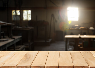 Wall Mural - Wooden table with blurred dark shadows and natural sun light workshop interior