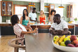 Diverse group of friends gather in a modern kitchen, socializing and preparing food